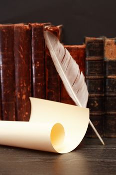 Ancient literature. Quill near scroll on background with old books