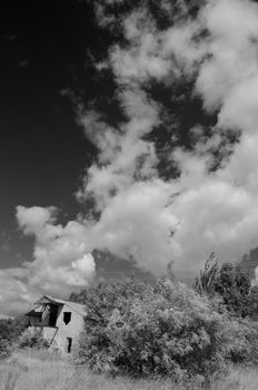 Rural landscape with clouds and abandoned house, black and white