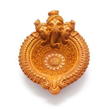 Close up of a beautifully carved designer handmade clay lamp with face of lord Ganesha isolated on white background.