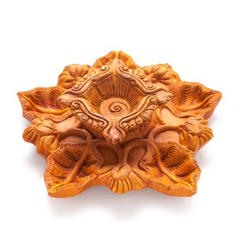 Close up of a beautifully carved designer handmade clay lamp isolated on white background.