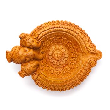 Top view of a beautifully carved designer handmade clay lamp with face of lord Ganesha isolated on white background.