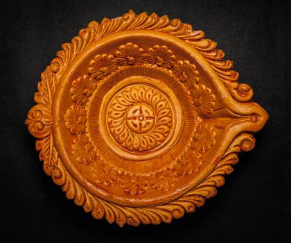 Top view of a beautifully carved designer handmade clay lamp on dark background.