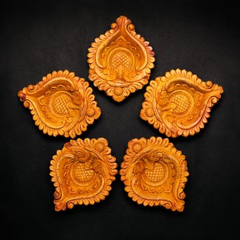 Top view Collage of beautifully carved designer handmade clay lamps isolated on dark background.