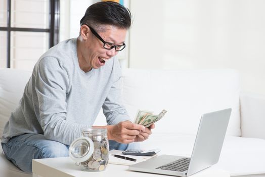 Mature 50s Asian man counting on money with excited face expression. Saving, retirement, retirees financial planning concept. 