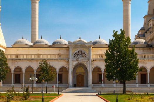 Exterior front view of Adana Sabanci Mosque, with six minarets, on bright blue sky background.