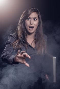 Worried businesswoman with laptop. Dark background.