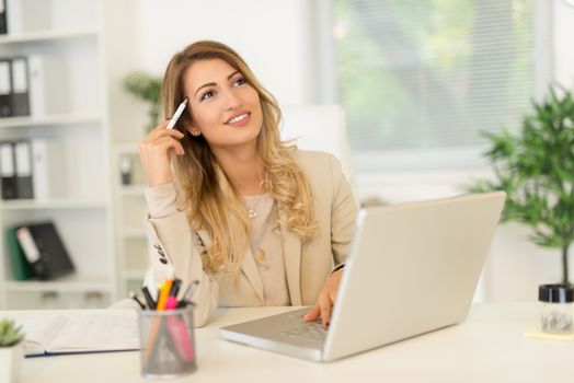 Beautiful young businesswoman sitting in the office and thinking.