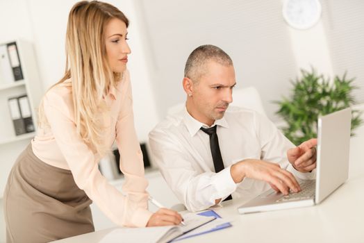 Young businesswoman and businessman working together on laptop in the office.