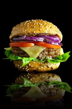 Freshly made burger with melted cheese, onions, tomatoes and lettuce filling