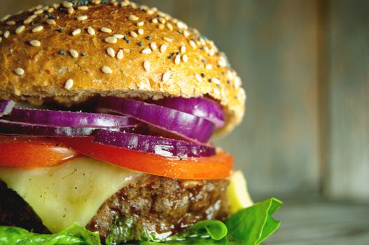 Close up of a gourmet burger with cheese, tomato and onion filling 