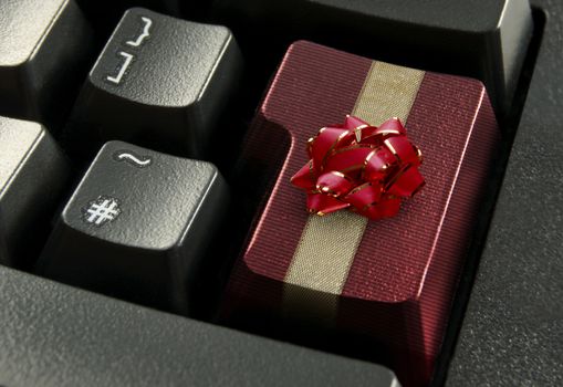 Red computer enter key wrapped with a gold gift ribbon and bow