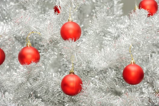 Red baubles hanging on silver artificial christmas tree, good as background