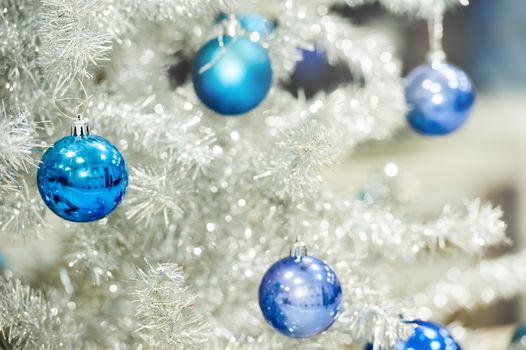 Blue baubles hanging on silver artificial christmas tree, good as background