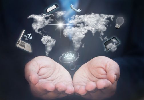 Business man holding a network of computer gadgets and communication icons stemming from clouds in the shape of the world map