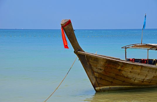 Traditional Thailand old vintage unpainted long tail boat in transparent turquoise water crossed with yellow float buoys