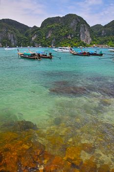 Paradise tropical sunny stone sea bay with sky blue green water and boats