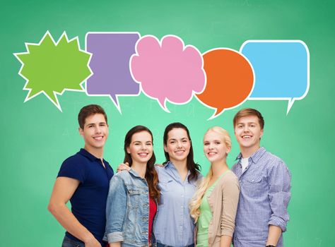 school, education, communication and people concept - group of smiling teenagers over green board background with text bubbles