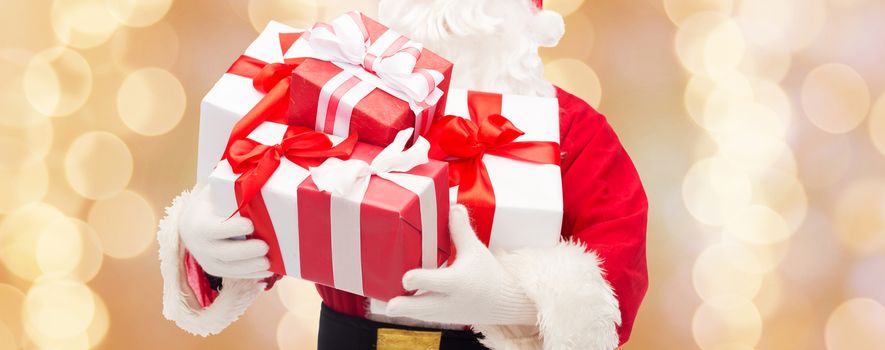 christmas, holidays and people concept - close up of santa claus with gift box over beige lights background