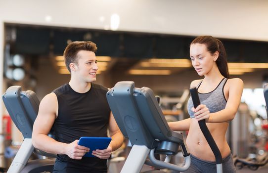 sport, fitness, lifestyle, technology and people concept - woman with trainer exercising on stepper in gym