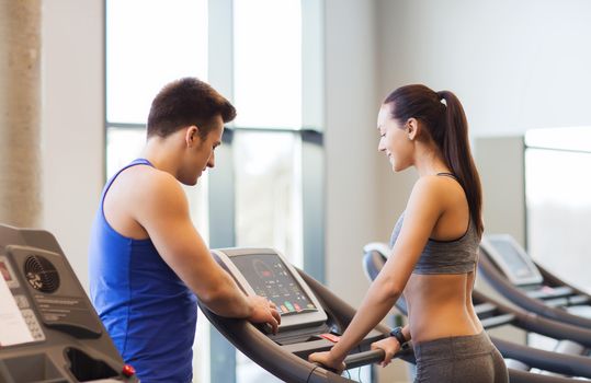 sport, fitness, lifestyle, technology and people concept - happy woman with trainer working out on treadmill in gym