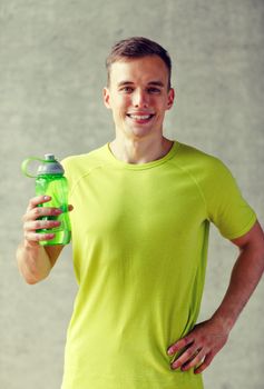 sport, fitness, lifestyle and people concept - smiling man with bottle of water in gym