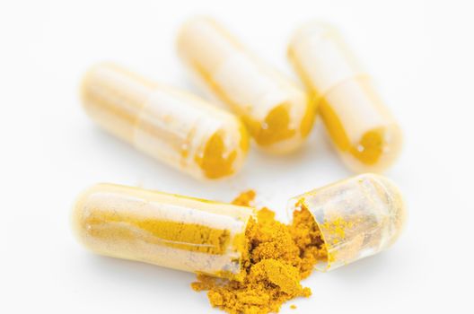 Turmeric herbal powder in capsule on white background.