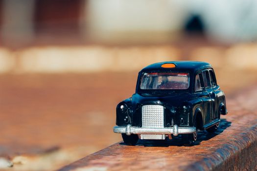 A model London Taxi parked on a rusted steel beam.