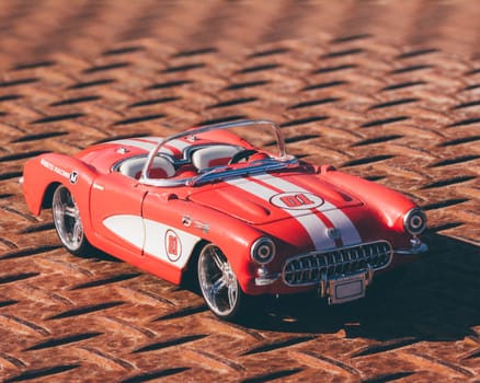 A red American classic car parked on rusted steel.