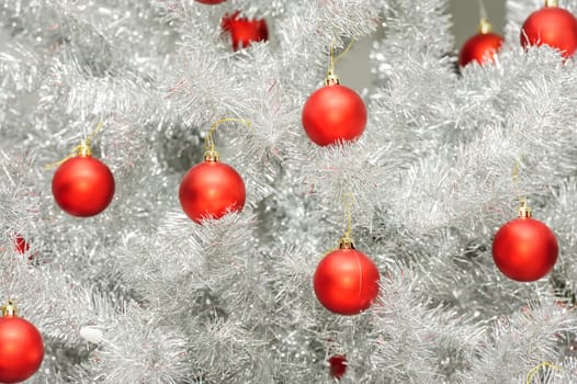 Red baubles hanging on silver artificial christmas tree, good as background