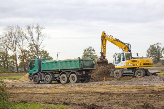 Excavator loading dumper truck tipper in sand pit