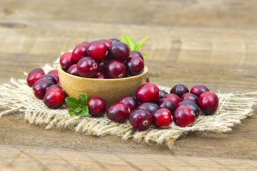 Cranberries in wooden bowl on wooden background.