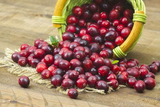 Cranberries in a basket on wooden background.