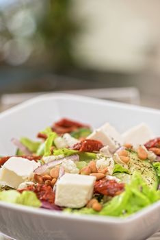 Salad feta cheese lettuce sausage cucumbers and pine nuts