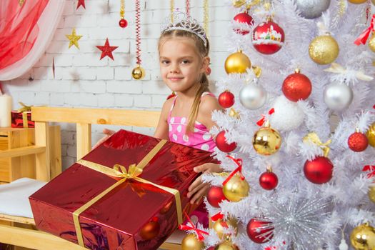 Six year old girl standing at the shop with a small gift from snowy Christmas trees