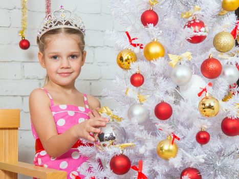 Four-year girl hangs balls on the Christmas tree Christmas snow