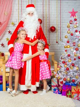 Santa Claus congratulates two girls sisters a Happy New Year and Merry Christmas in the home New Years interior