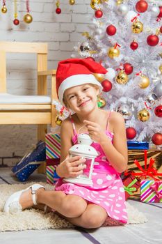 Six year old girl sitting on a mat at a snowy Christmas trees