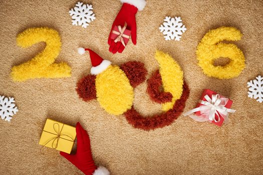 New Year 2016. Christmas.Funny monkey in Santa hat and banana,presents,snowflakes.Happy festive still life,yellow digits handmade, hands in red gloves.Party decoration, unusual holiday card, copyspace