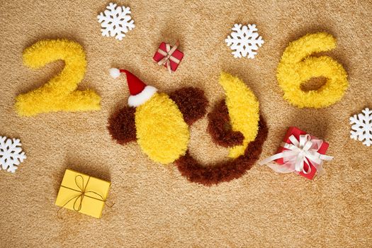 New Year 2016. Christmas.Funny monkey in Santa hat with banana,presents. Happy vivid festive still life.Yellow digits handmade. Party decoration, gift box, shaggy unusual holiday card, copyspace