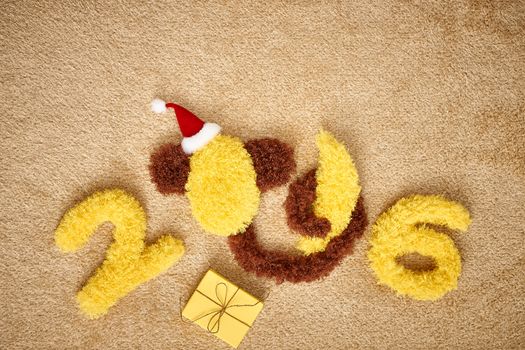 New Year 2016. Christmas.Funny monkey in Santa hat with banana and present. Happy vivid festive still life.Yellow digits handmade. Party decoration, gift box, shaggy unusual holiday card, copyspace
