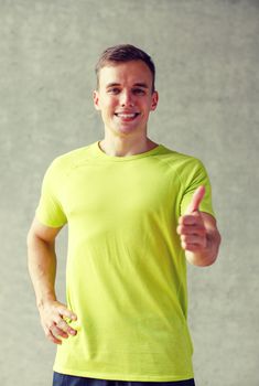 sport, fitness, lifestyle and people concept - smiling man showing thumbs up in gym