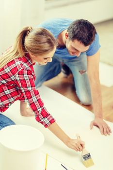 repair, building and home concept - smiling couple smearing wallpaper with glue