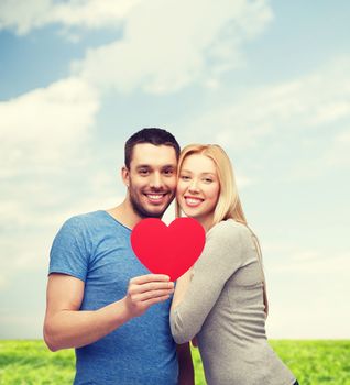 couple, love and family concept - smiling couple holding big red heart