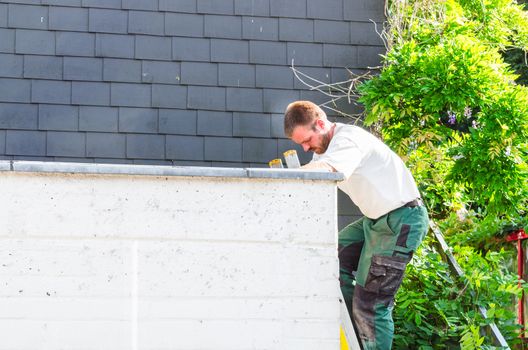 Construction worker on a ladder that is leaning against a flat roof.