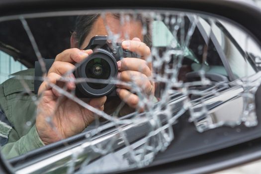 Mirror image of a photographer in the broken car mirror