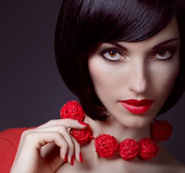 Fashion beauty portrait of sexy brunette woman, silky bob hairstyle on dark. Sensual lady with stylish necklace mysteriously looks. Brown-eyed girl, luxury makeup, red lips. People face closeup