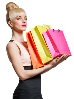 Beautiful woman holding shopping bags isolated on white background. Confident blonde girl boasting purchases. Pinup hairstyle, fringe, pink bow. Happy fashionable shopaholic. Glamorous bright makeup