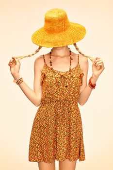 Beauty  playful boho slim model woman in orange hat, romantic style, people. Hippie young joyful girl with blonde pigtails in floral fashion sundress happy, enjoying, having fun. Summer look. Toned 