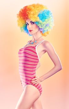 Fashion sexy beauty model slim woman in swimsuit sensually looks, vivid unusual creative people. Provocative attractive girl with trendy necklace on peach, toned. Multicolored afro hairstyle, makeup