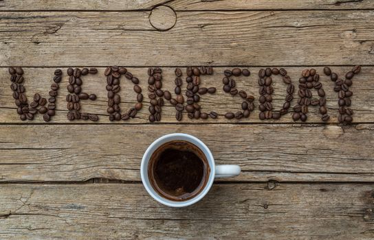Cup of coffee on wooden background and WEDNESDAY coffee beans 